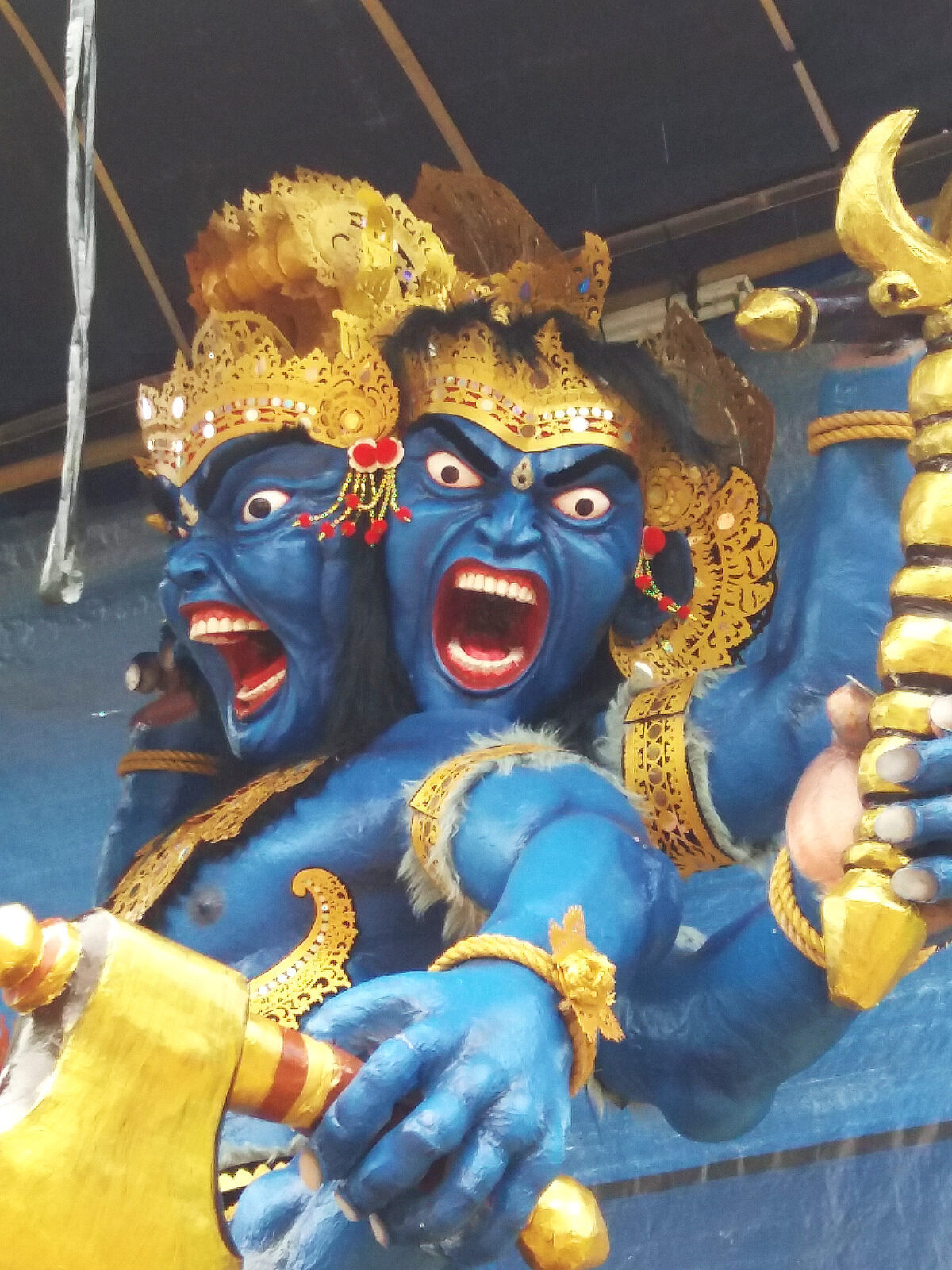 An ogoh-ogoh in the making — a blue demon figure, gilded and fanged, of the kind each village builds for the night before Nyepi.