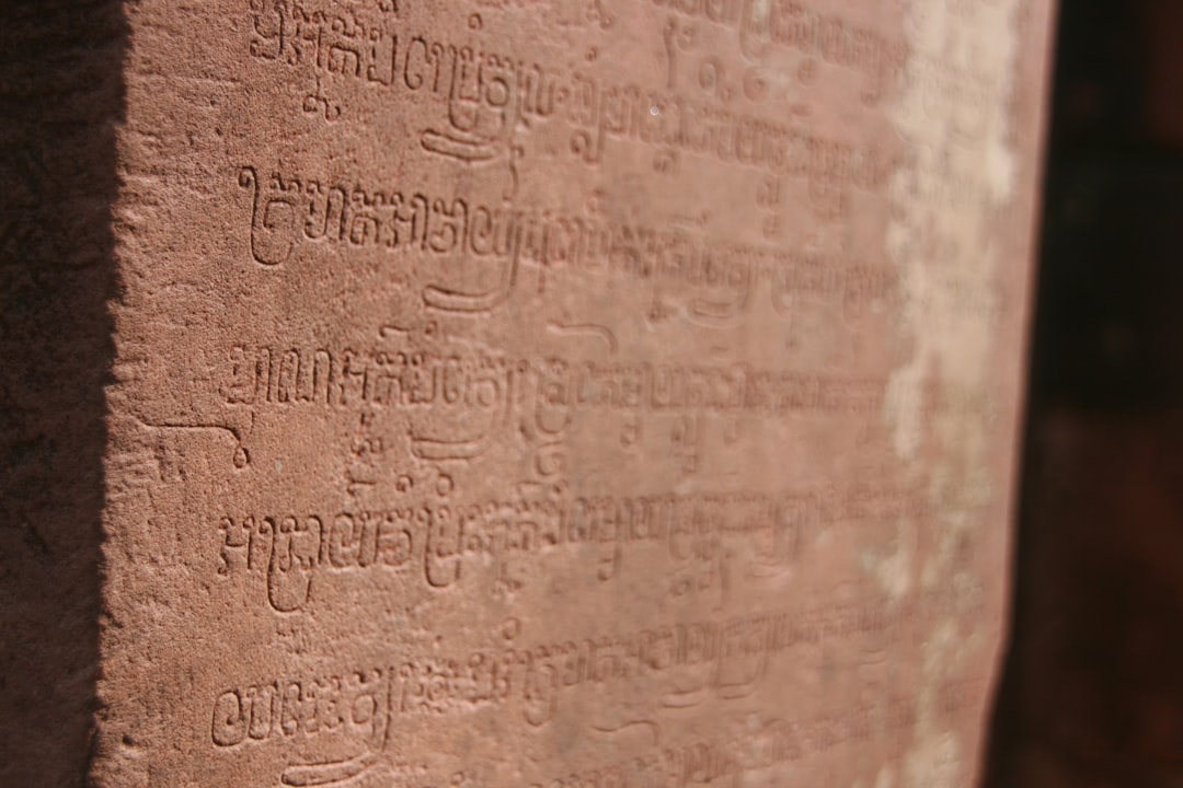 Aksara Bali script beside Latin lettering on a village plaque in Jimbaran