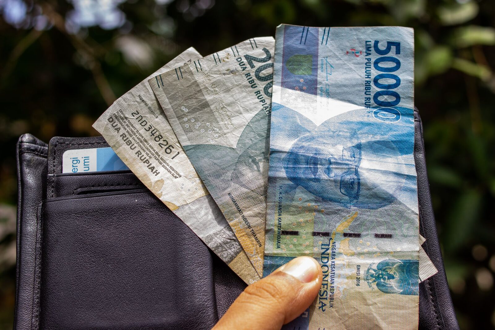 Rupiah tucked into a wallet. Pulling cash from a bank ATM sidesteps the changer question entirely. Tap any image for its source and licence.