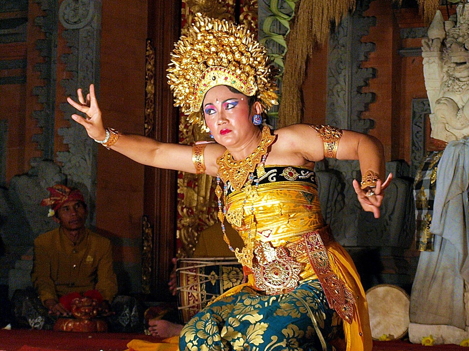Close on a dancer's gilded headdress and curled fingers.