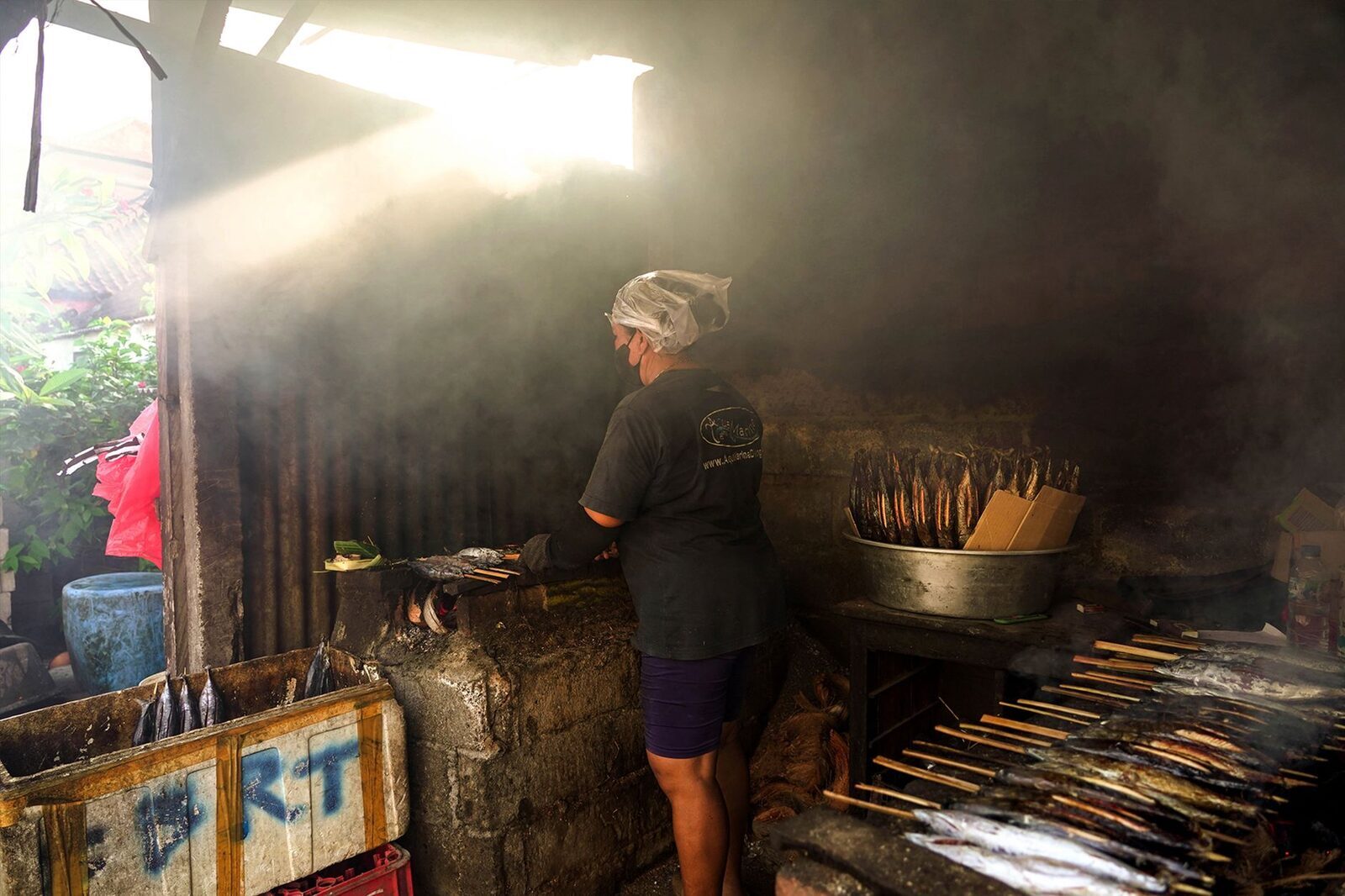 A cook working a smoky beachfront grill.