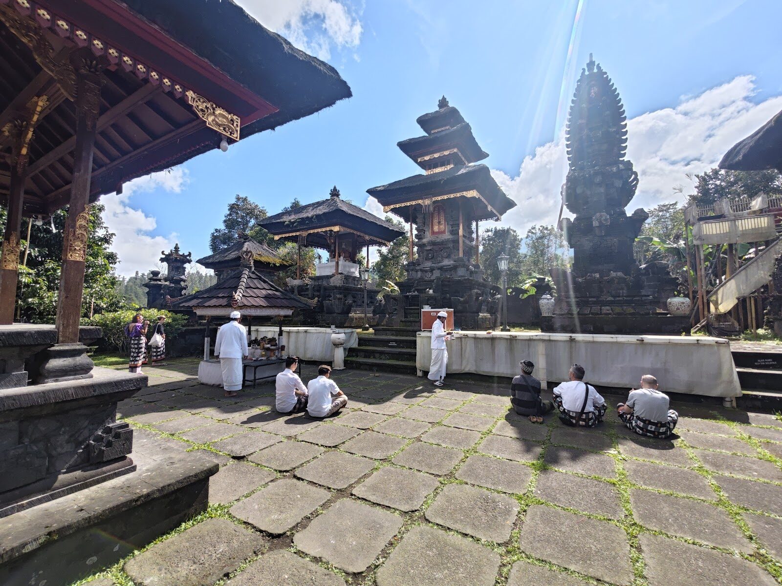 Inside the complex: black meru towers and a split gate, with worshippers resting on the stone.