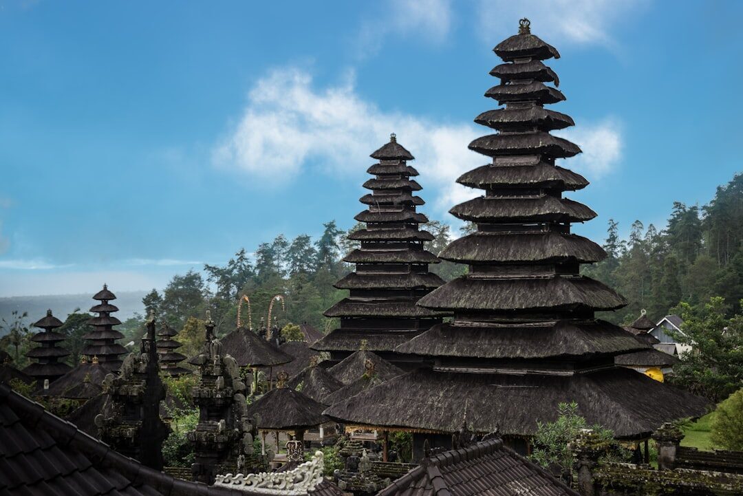 Tiered meru against a clear sky — the dark palm-fibre roofs that give the complex its silhouette.