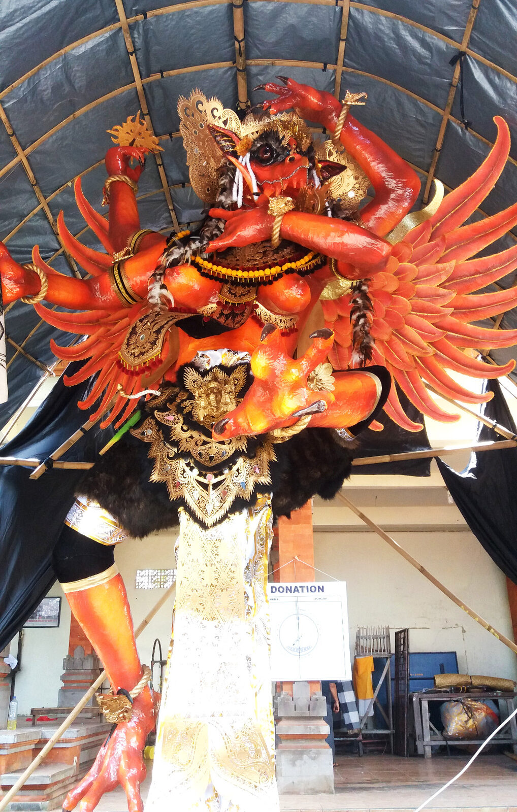 A red-and-gold winged effigy in its shelter before the night's parade.