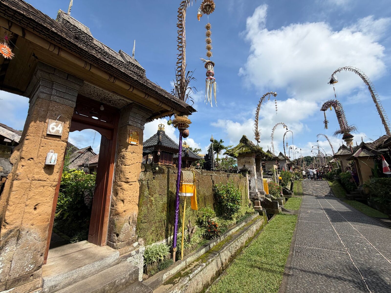 Penjor over a family gateway, the decorated bamboo bending across the entrance.