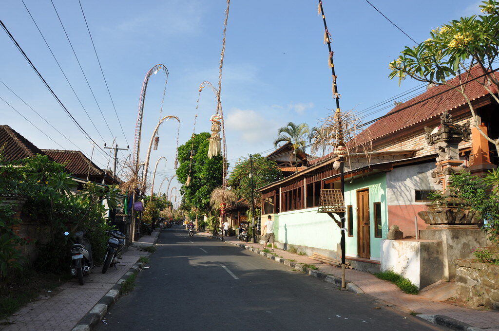 A quiet village street lined end to end with penjor through the Galungan season.