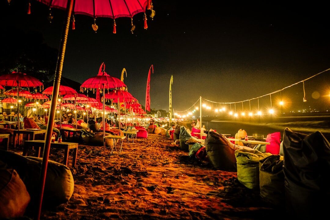 The beachfront warungs at night, strung with lights under red parasols.