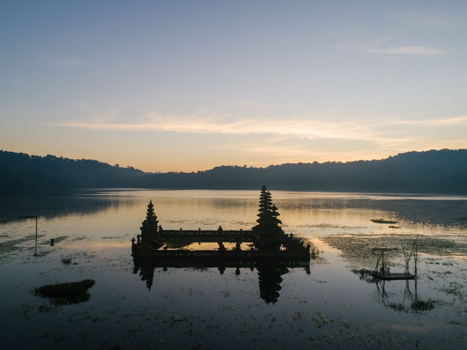 A small lakeside shrine standing in the still water at first light, before the wind and mist arrive.