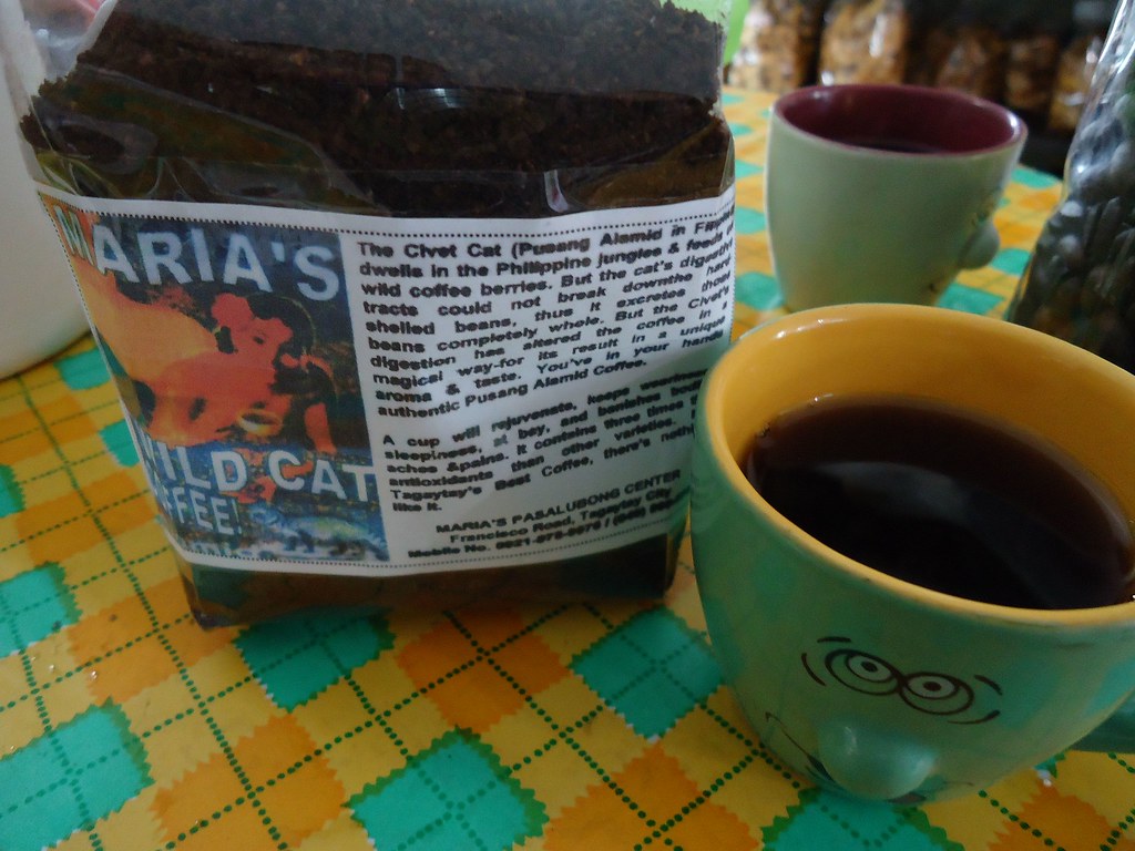 A roadside kopi luwak stall with civet-coffee signage and a cup