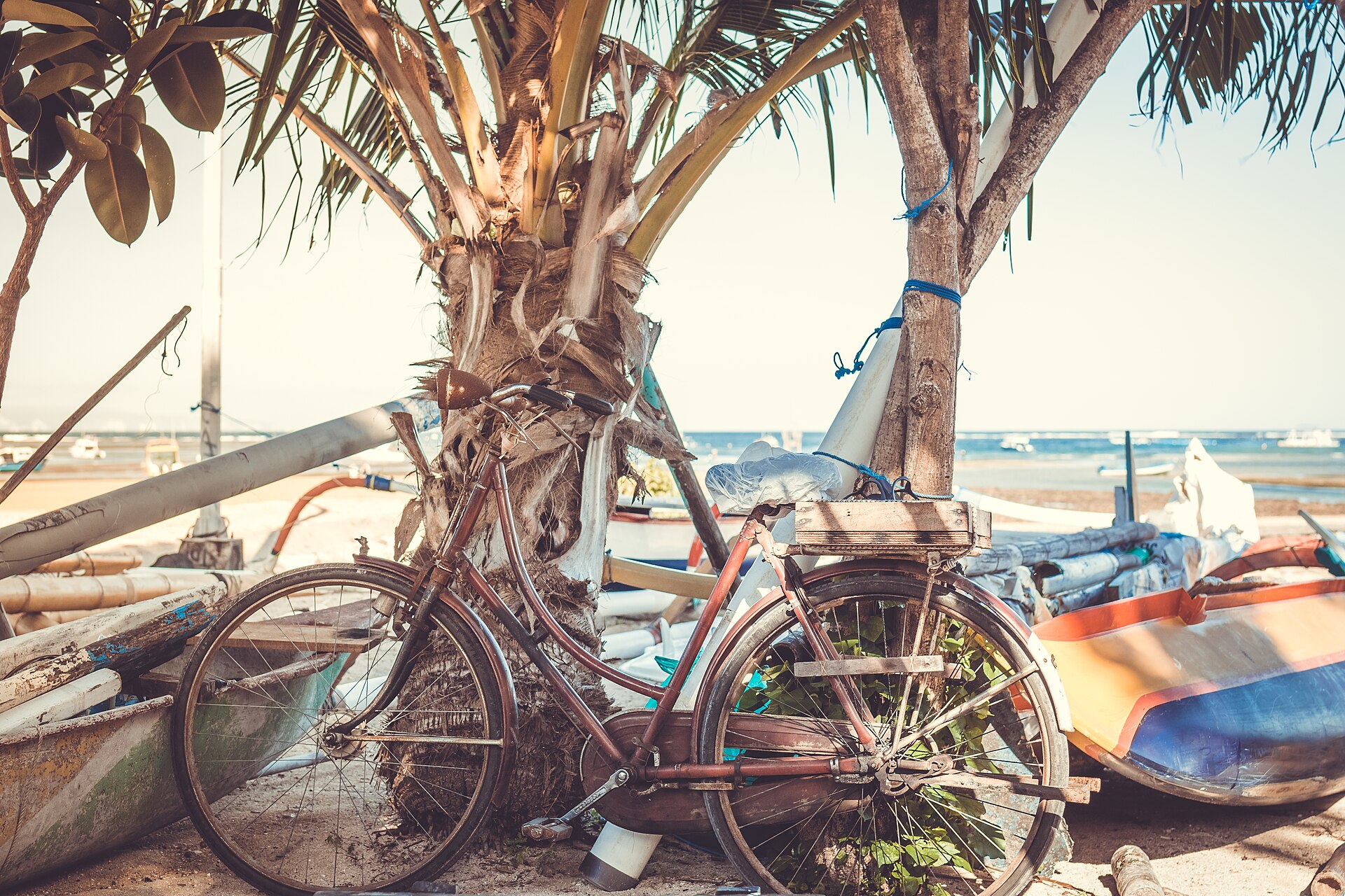 A beach cruiser leaning against an outrigger boat on the sand at Sanur