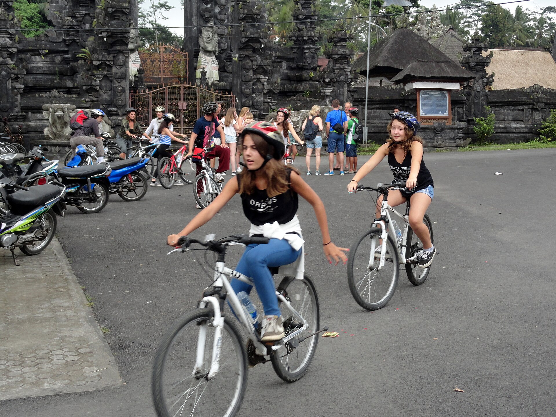 Cyclists on a country road past a Balinese village