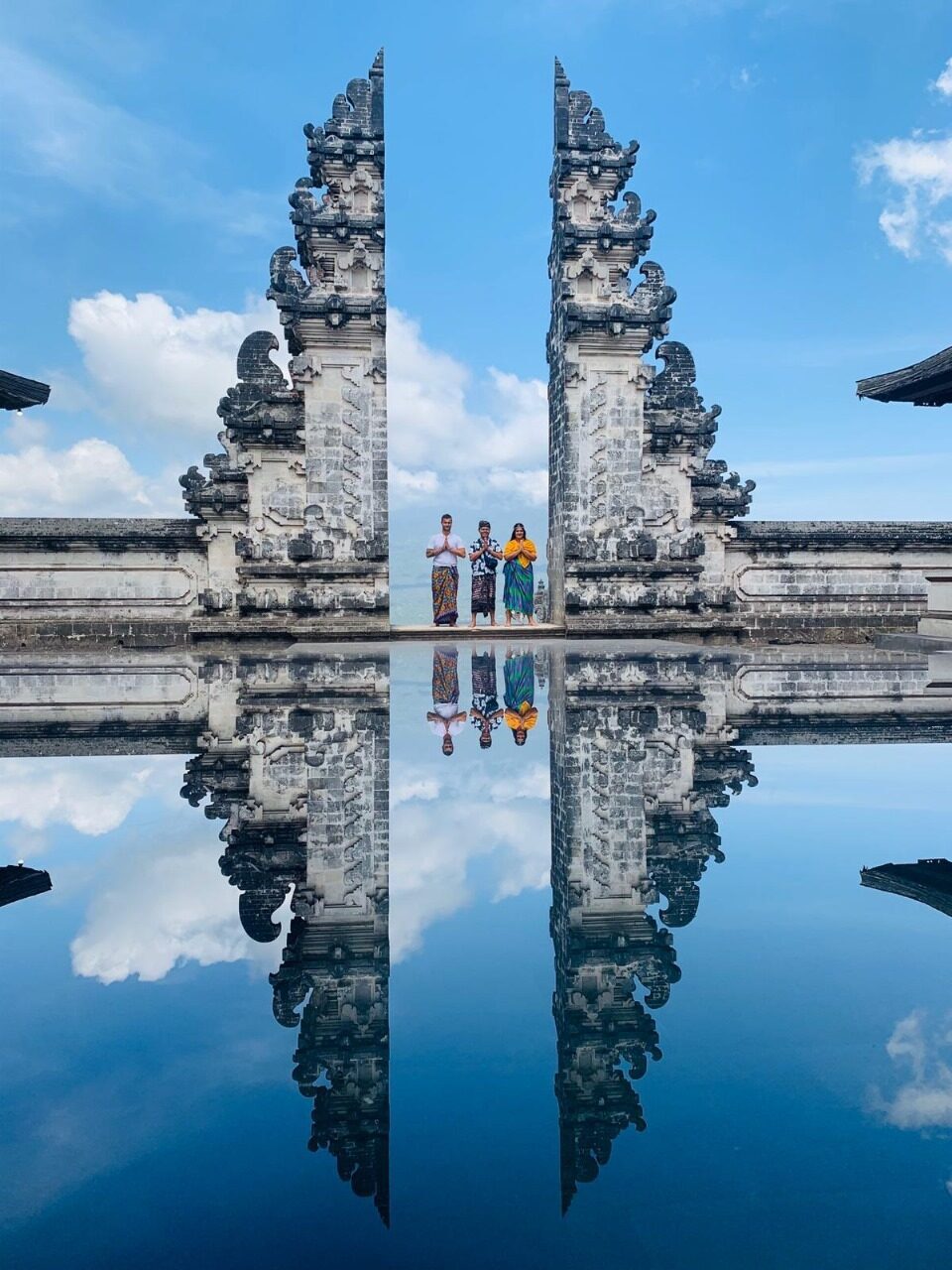 The shot you've seen: the split gate mirrored below Mount Agung. There is no pool — the 'reflection' is a phone held over a small mirror, and it comes with a two-to-three-hour queue in high season.
