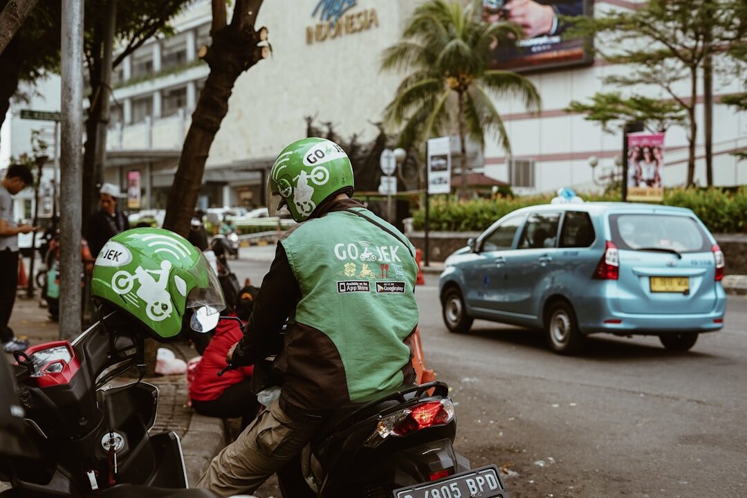 Green-jacketed app drivers waiting on their bikes — the same riders do car trips and cheap motorbike rides.