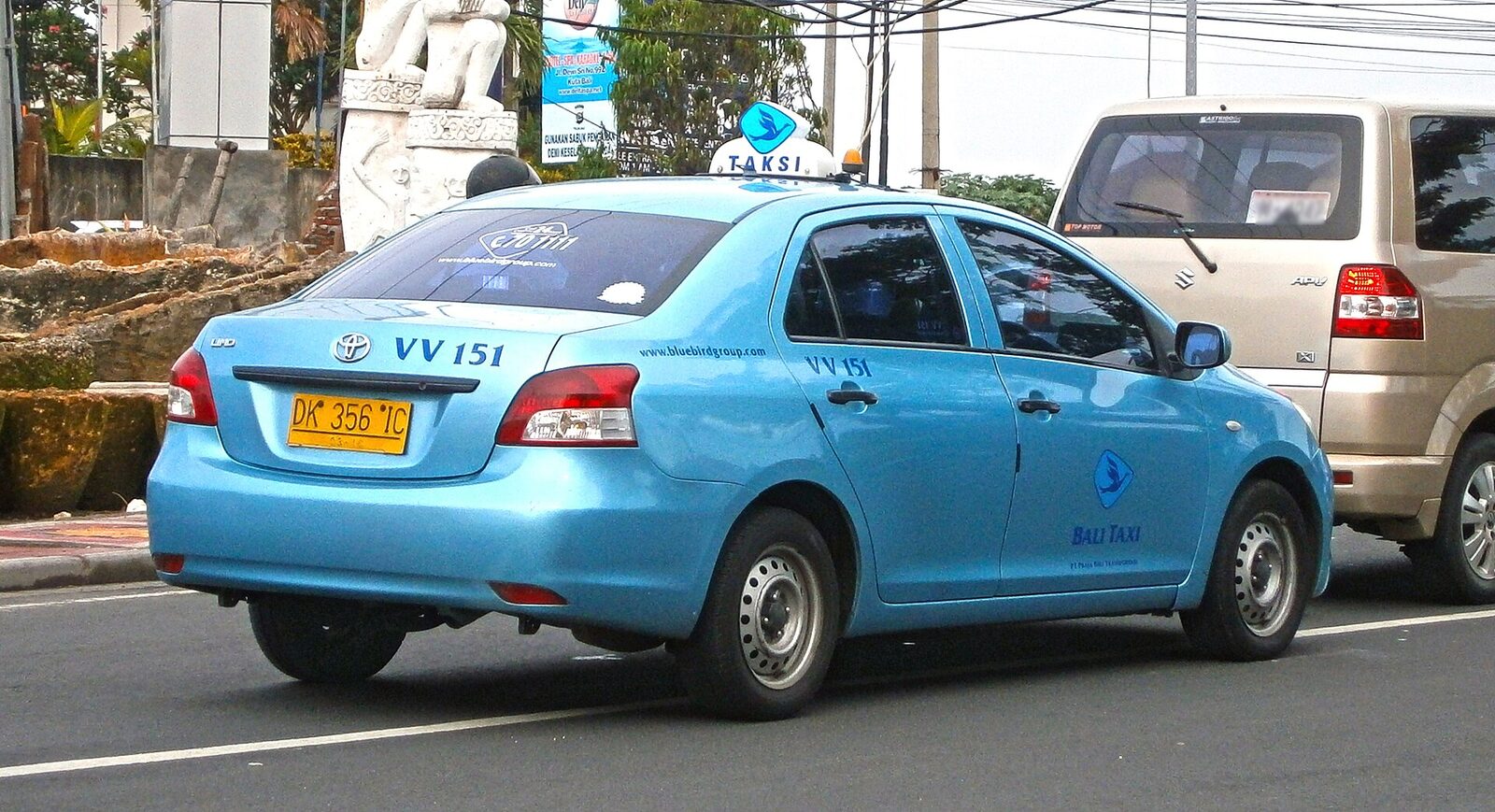 A Blue Bird metered taxi in its trademark blue with the little bird on the roof — the company locals trust, and the one the copycats imitate.