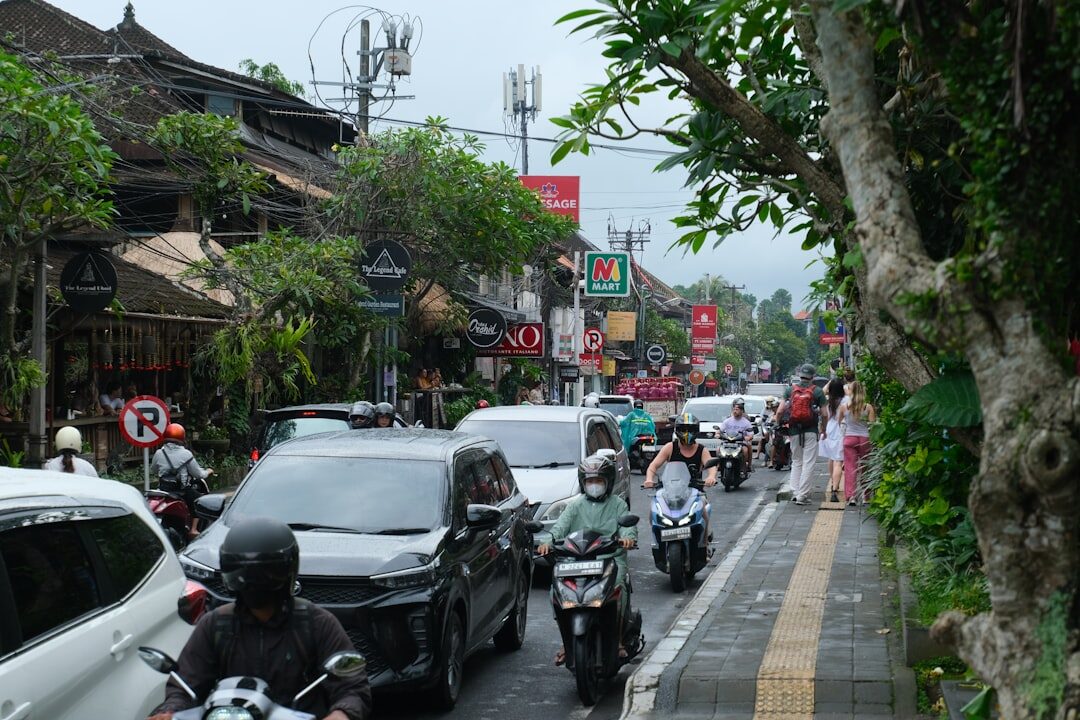 Cars lining a narrow street bumper to bumper, scooters squeezing down the edge.