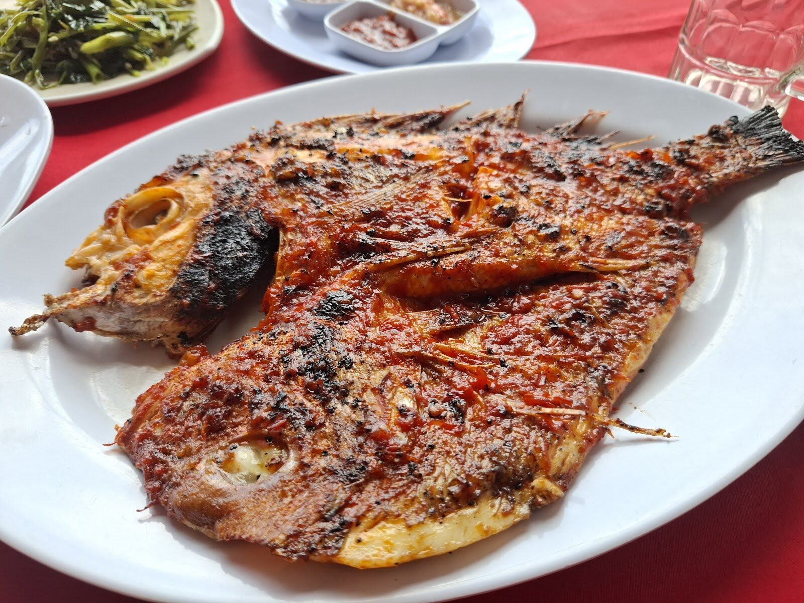A whole fish grilled with sambal — the Jimbaran house style, cooked over coconut husks.