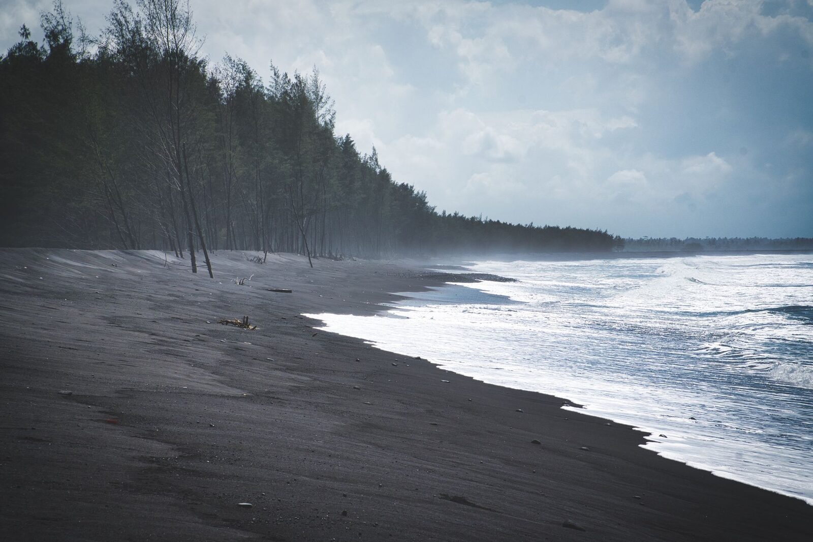 Black volcanic sand and open water on the north coast — the colour that catches first-timers off guard.
