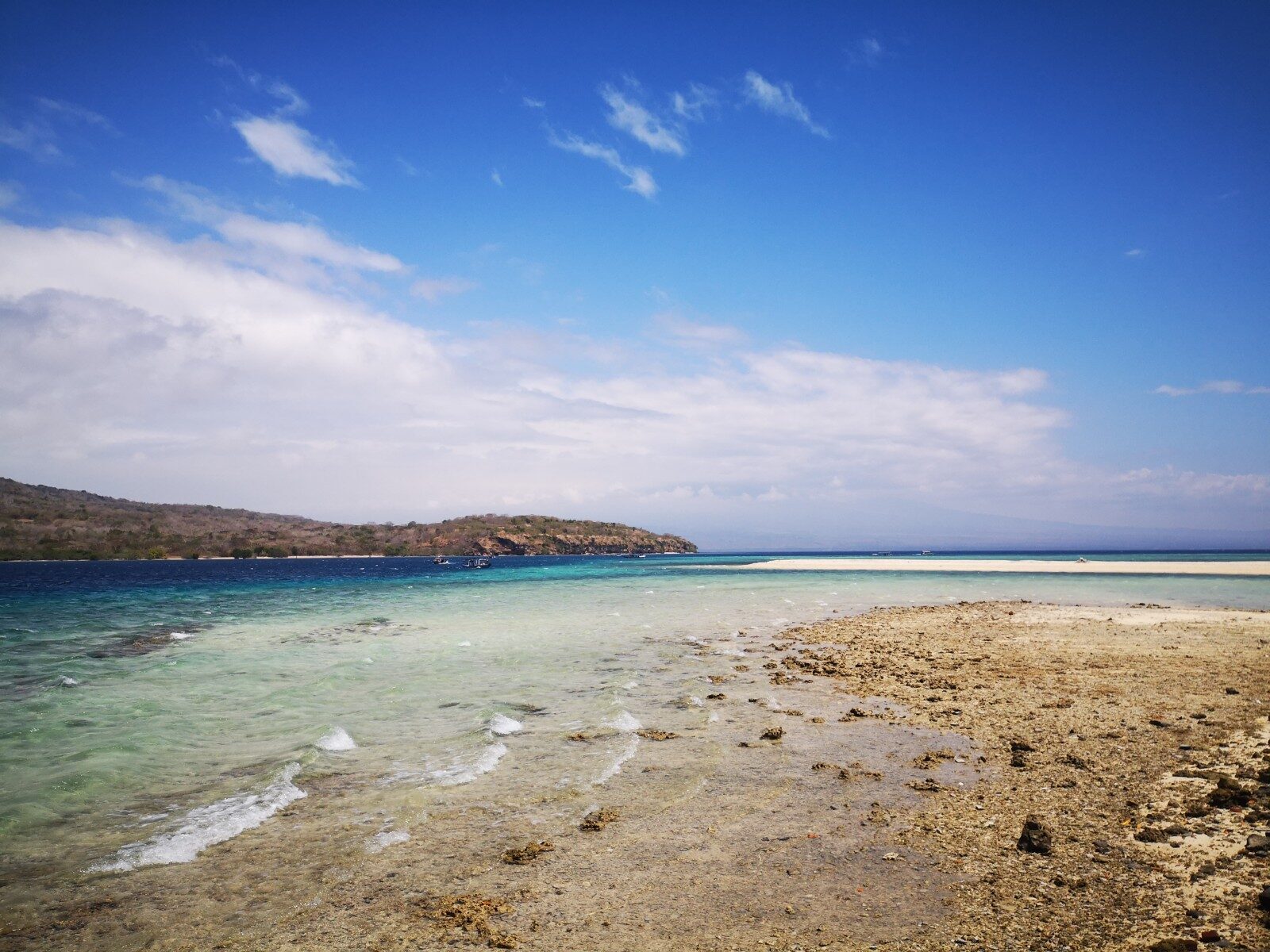 The shallow reef flat off Pemuteran's beach, a headland closing the bay.