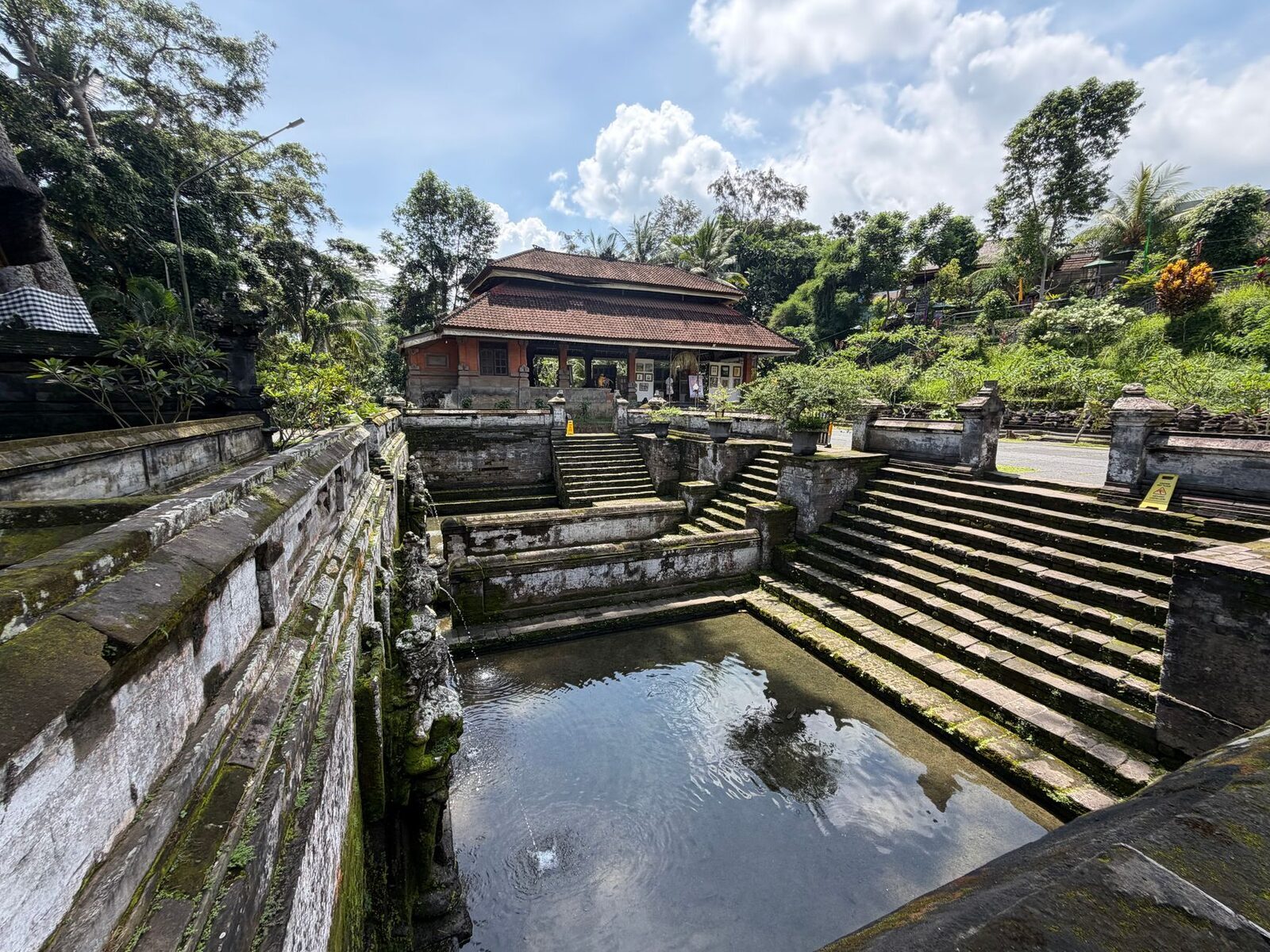 A stone-lined bathing pool set into a garden terrace — the worn masonry of a north-Bali petirtaan. (A Bali stone bathing pool.)