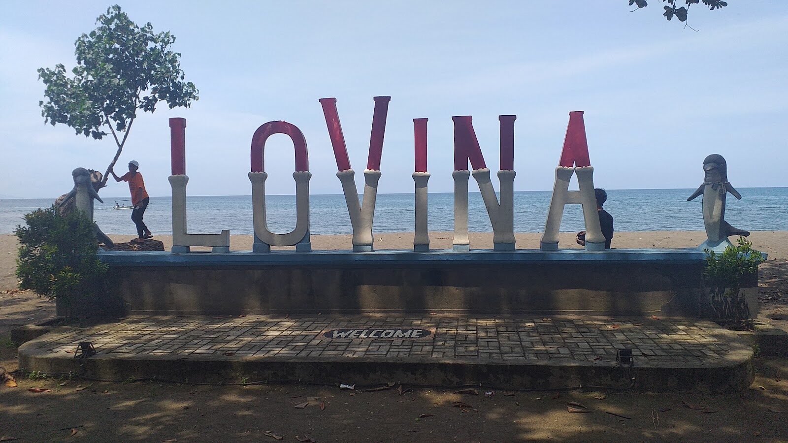The LOVINA sign and its dolphin statues — the town's cheerful, unmistakable marker.