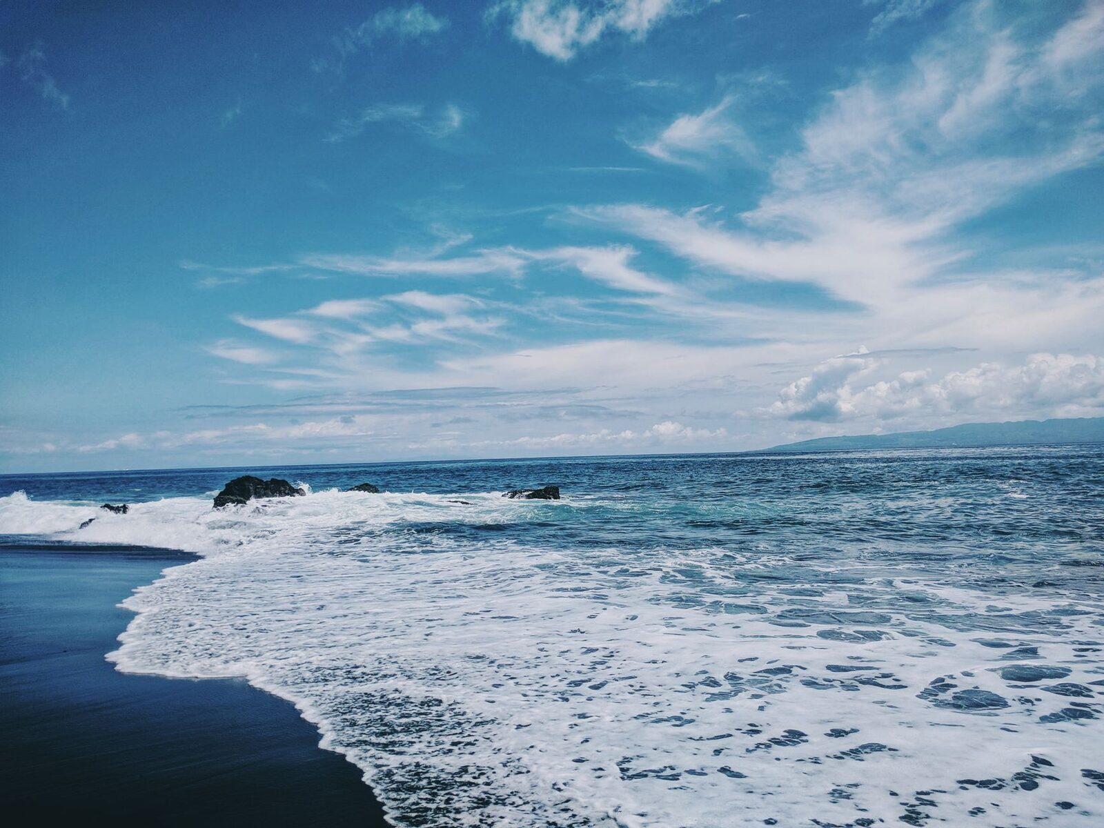 Black sand under a bright sky — pretty in its own way, just not the turquoise-and-gold most people picture.
