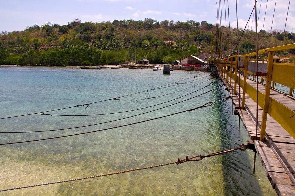 The suspension bridge from the side, its cables strung over the channel.