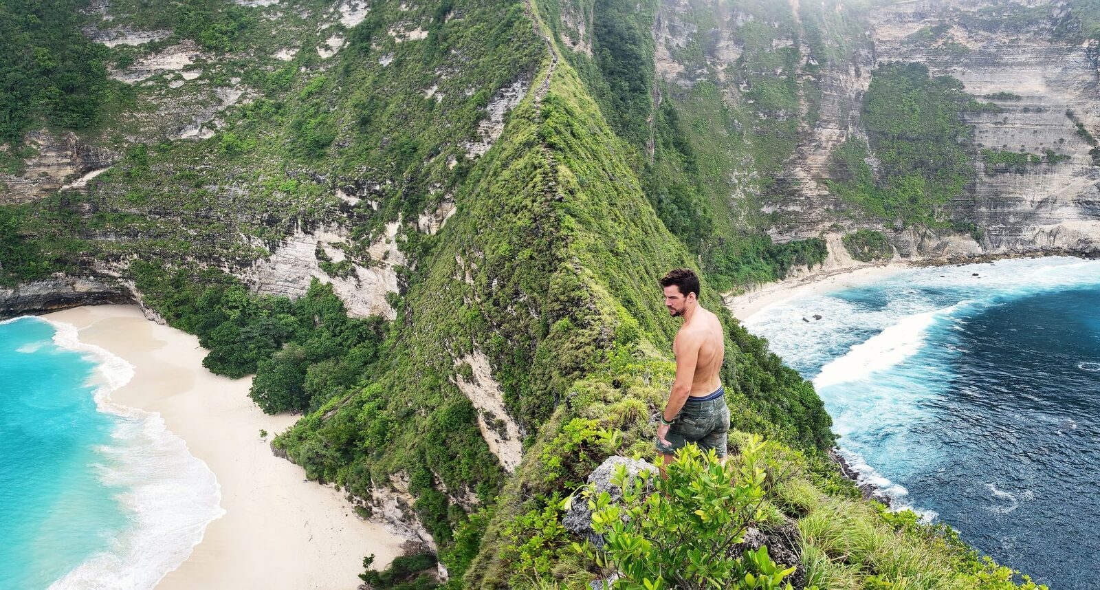 A visitor out on the steep, exposed cliff at Kelingking — the kind of unfenced edge that has caused serious falls.