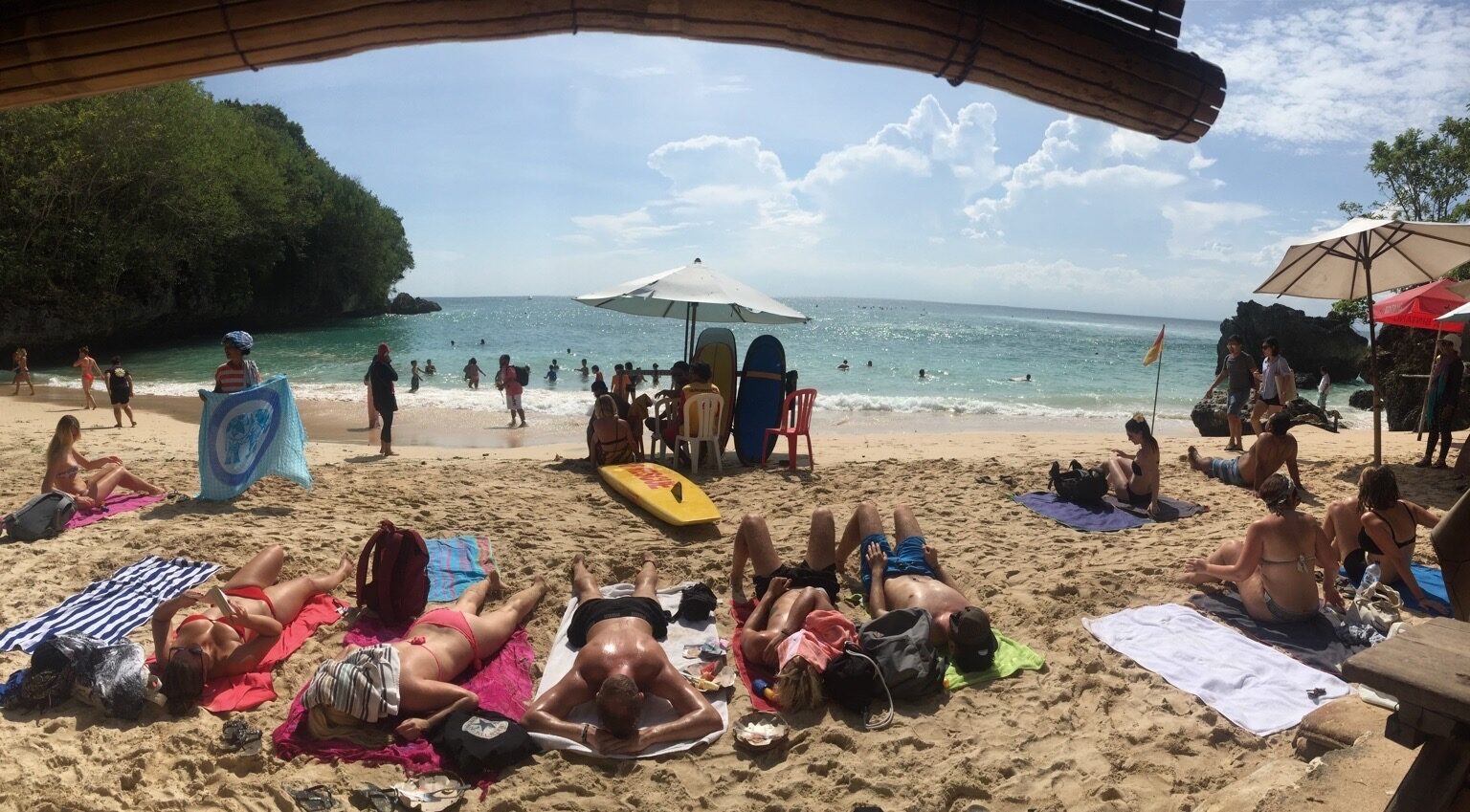 Beachgoers on the sand, framed by the rock arch at the foot of the stairs.
