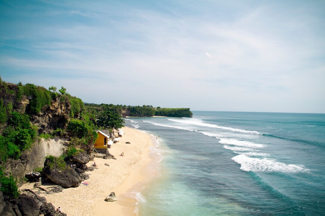 A calm Bukit cove with loungers set out on the sand — easy, swimmable water.