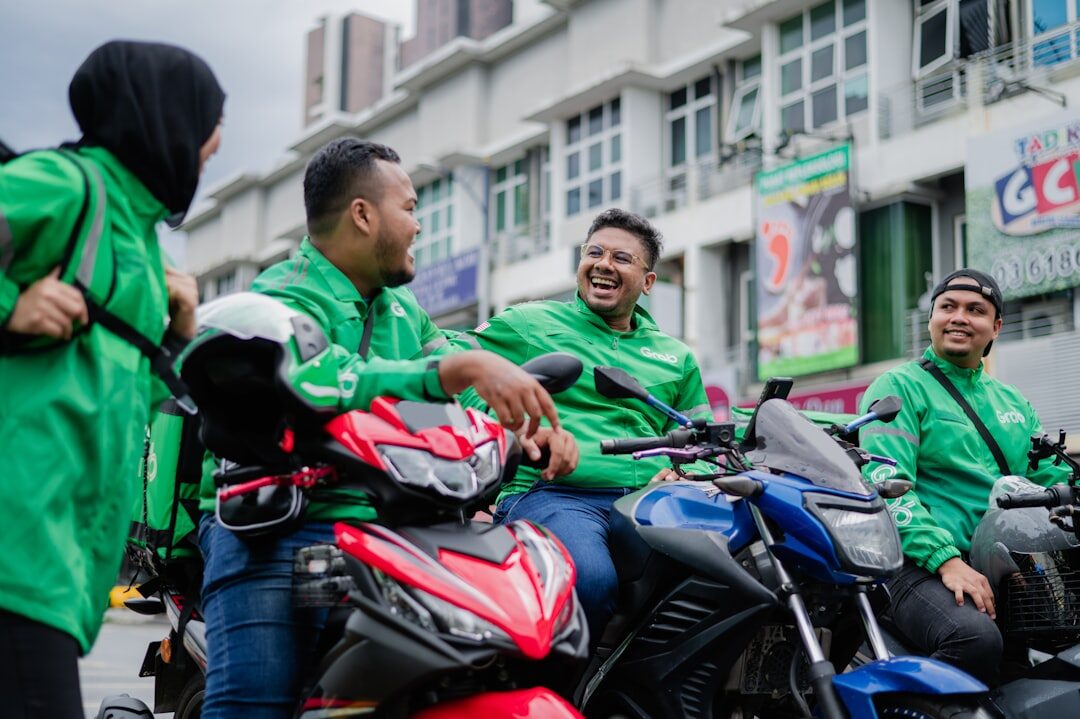 A cluster of Grab drivers wait together by their bikes between jobs.