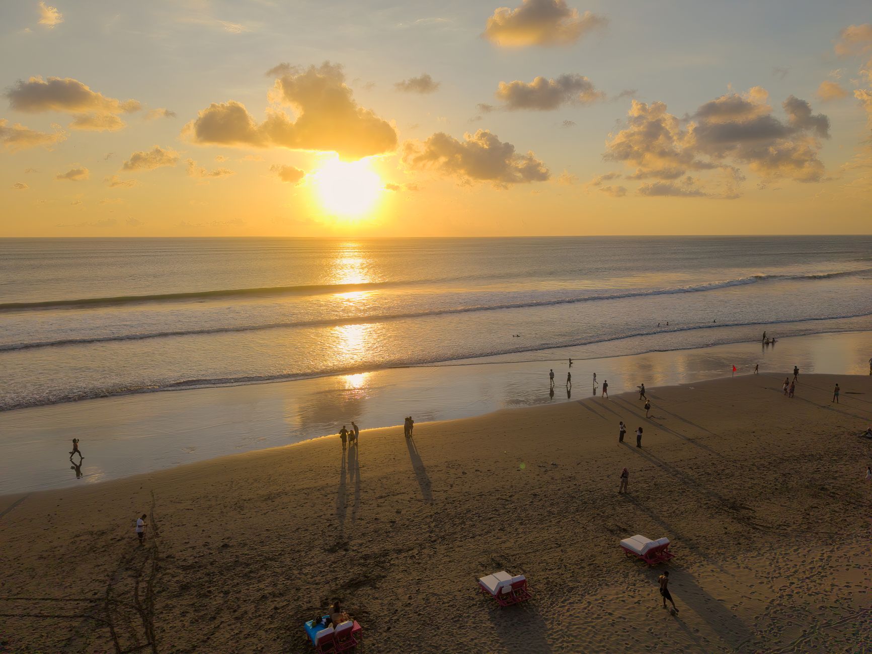 A glowing sunset over Seminyak beach, people in silhouette