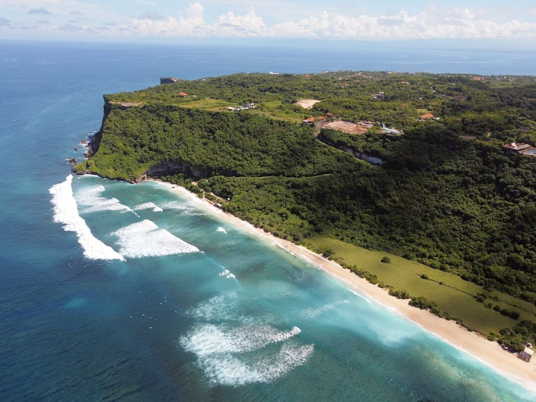 An aerial of swell wrapping along a headland and peeling down the beach.