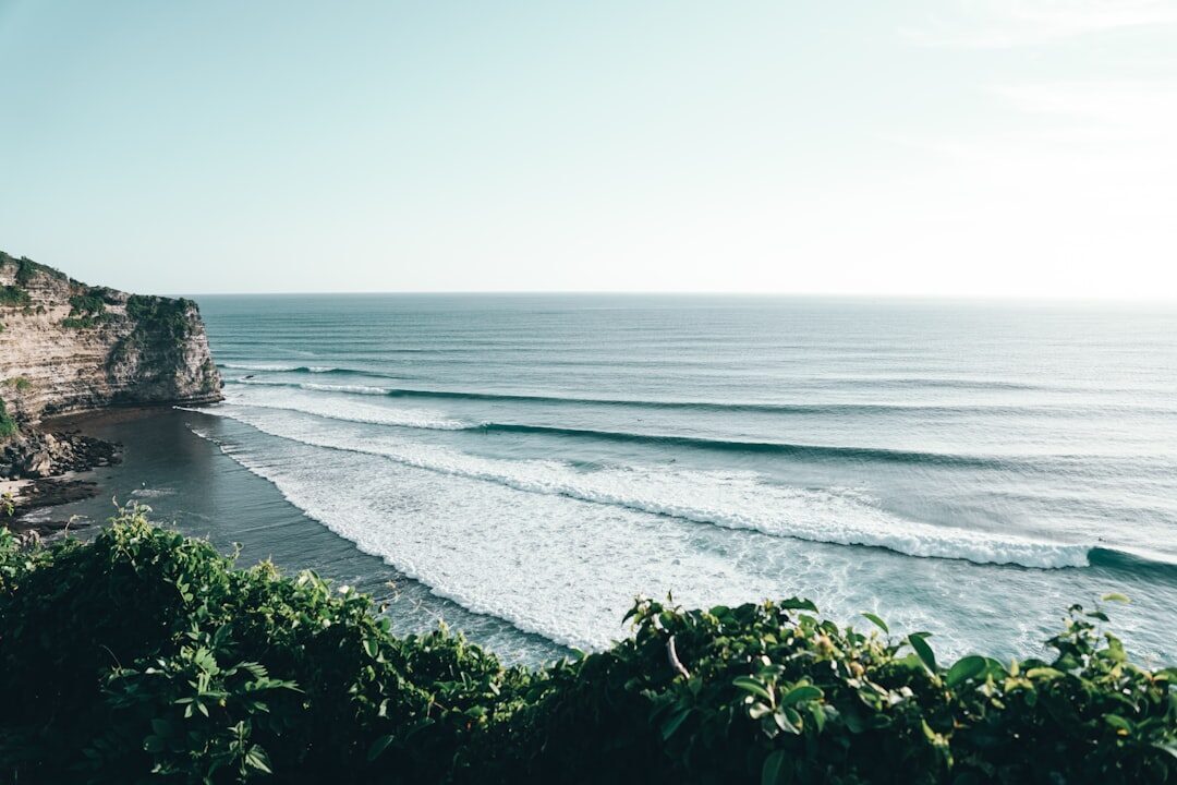 A tall sea-cliff above a long peeling reef wave — the classic Bukit set-up.