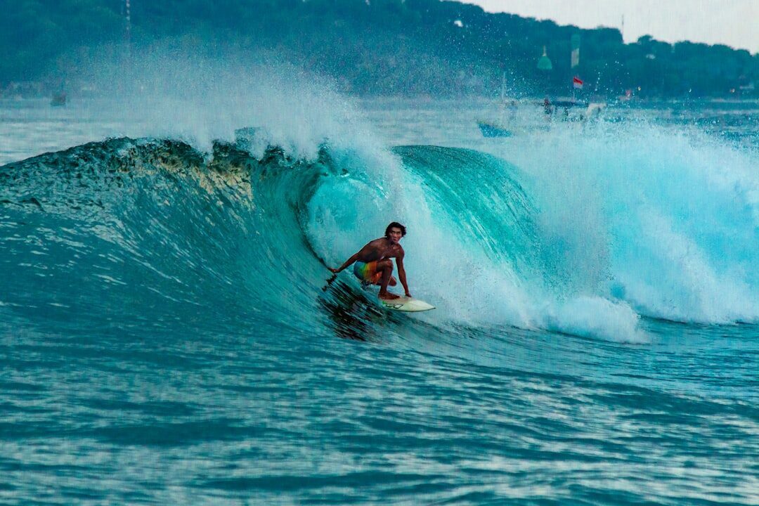 A surfer deep inside a heavy, turquoise reef barrel — the kind of wave the Bukit's reefs throw on a working swell.
