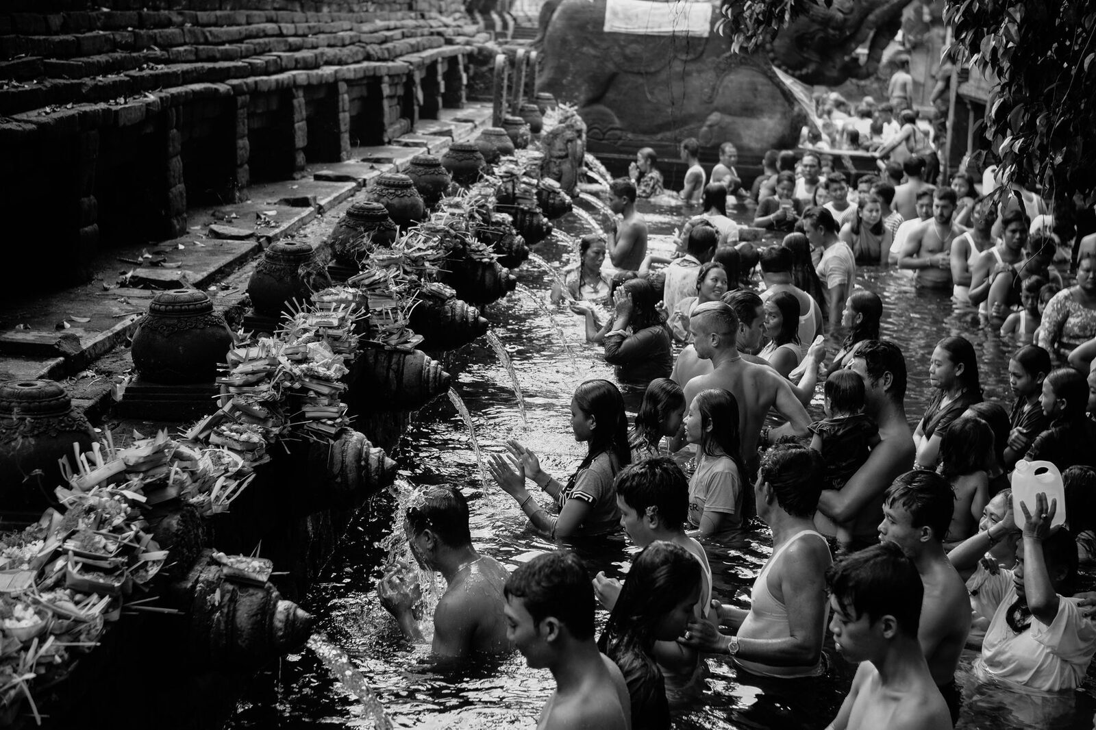 The crowd at the spouts in black and white — a working temple, not a quiet water feature.