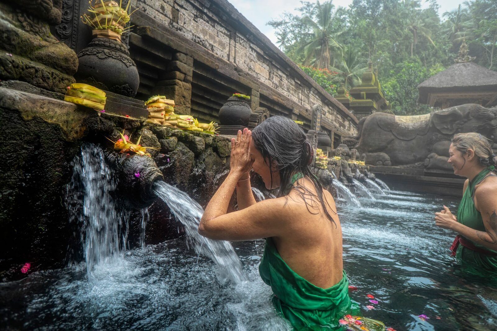 A bather putting her face fully into the flow, the way the ritual is meant to be done.