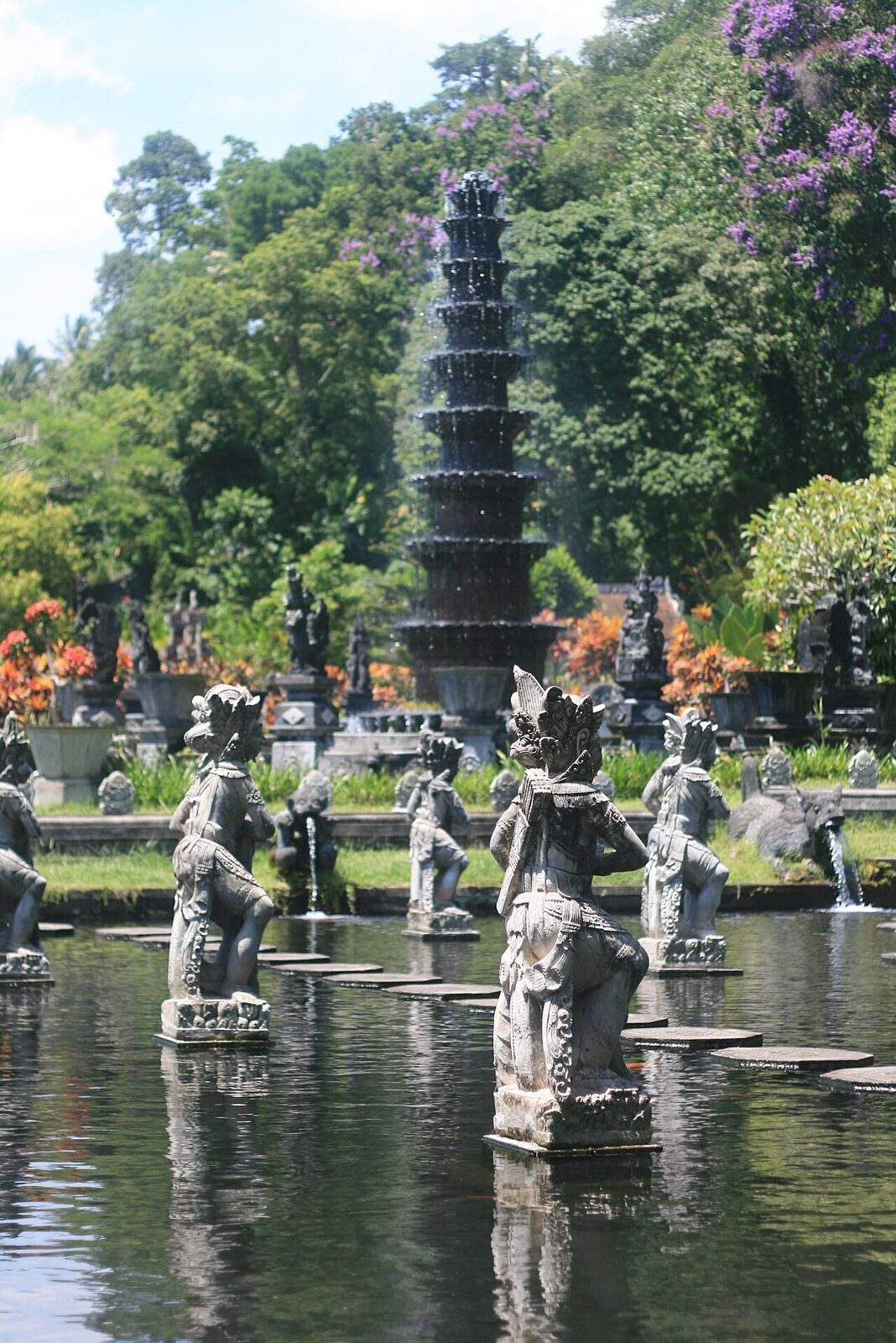 The fountain and its ring of stone statues, a few visitors picking their way around the pond.