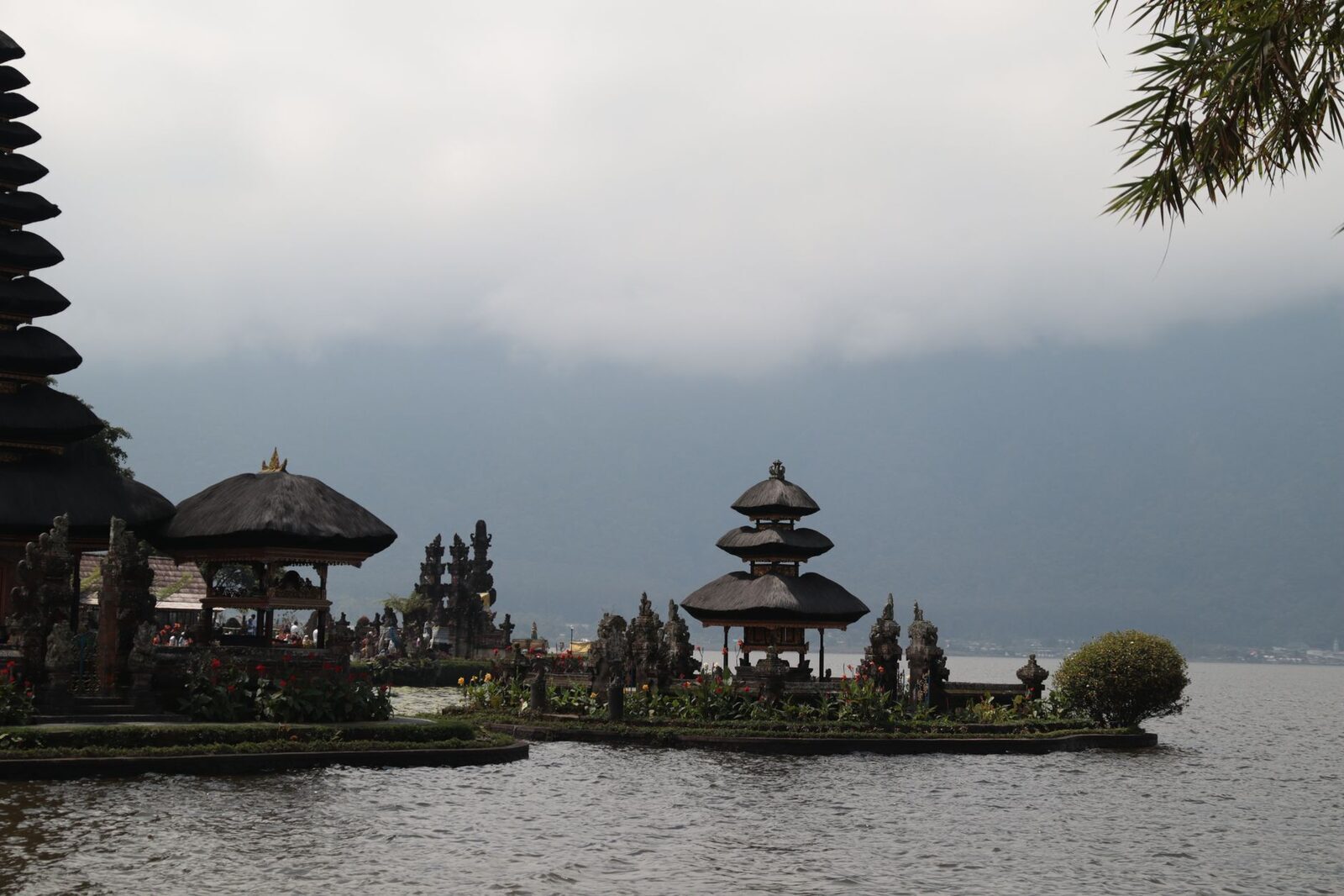 The meru and pavilions mirrored in a calm patch of Lake Beratan.