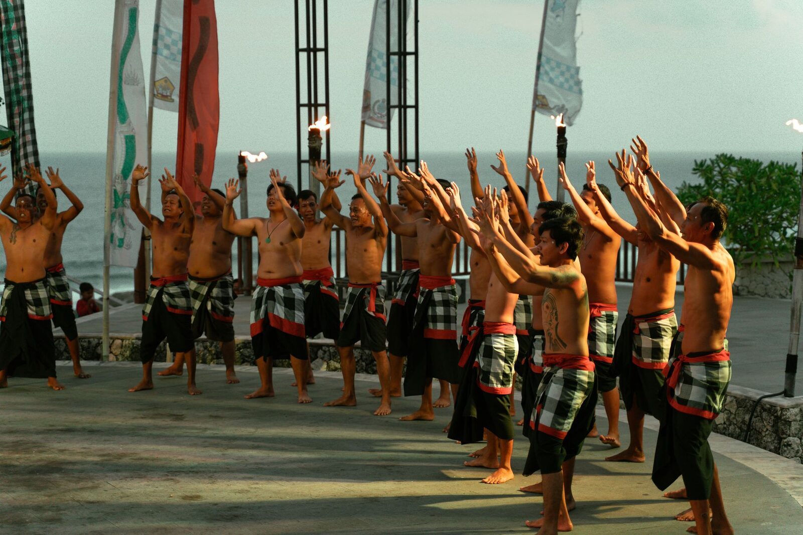 The chorus on its feet, arms up, the Indian Ocean at their backs.