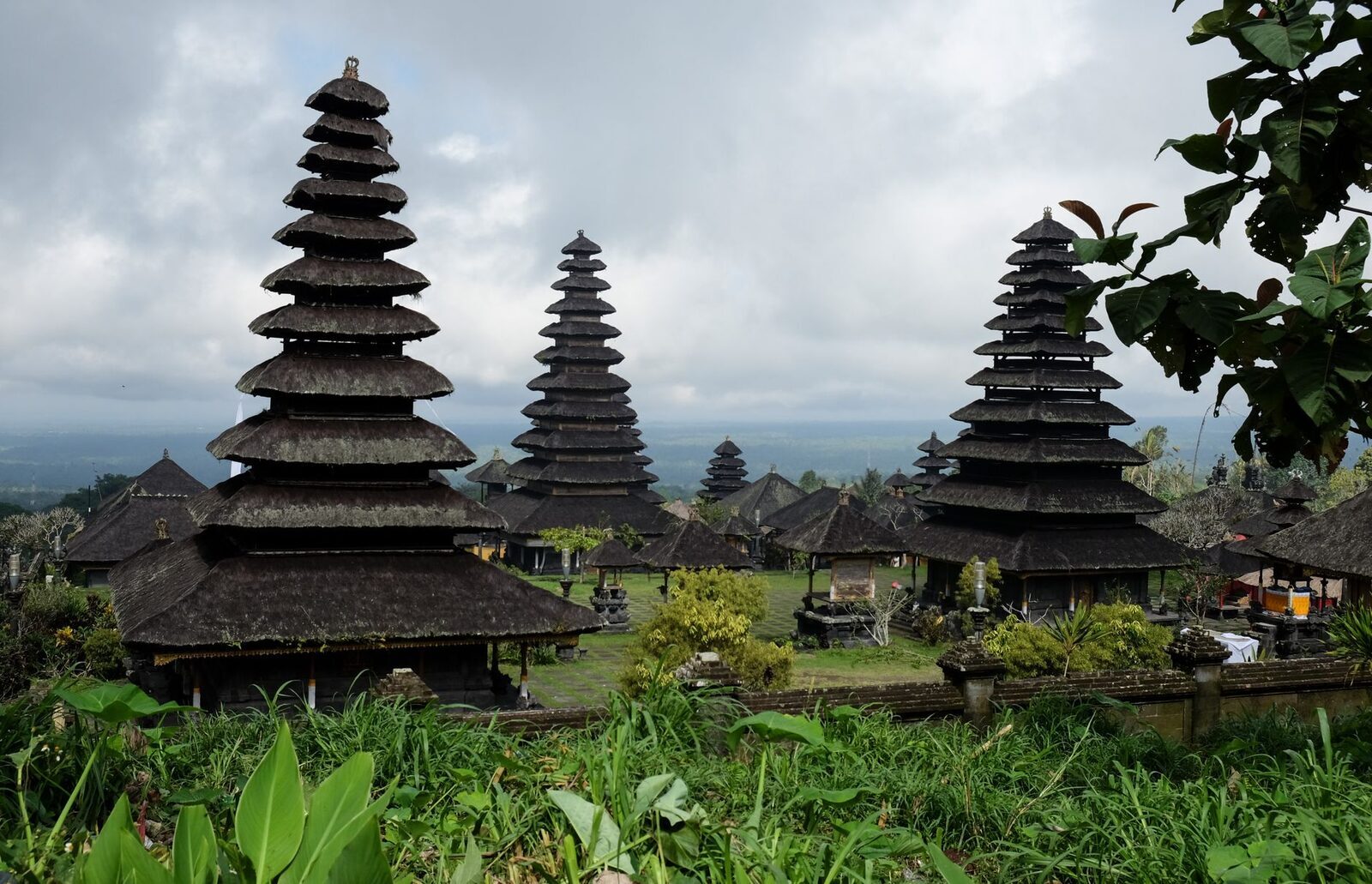A pair of black-thatched meru rising from temple greenery.