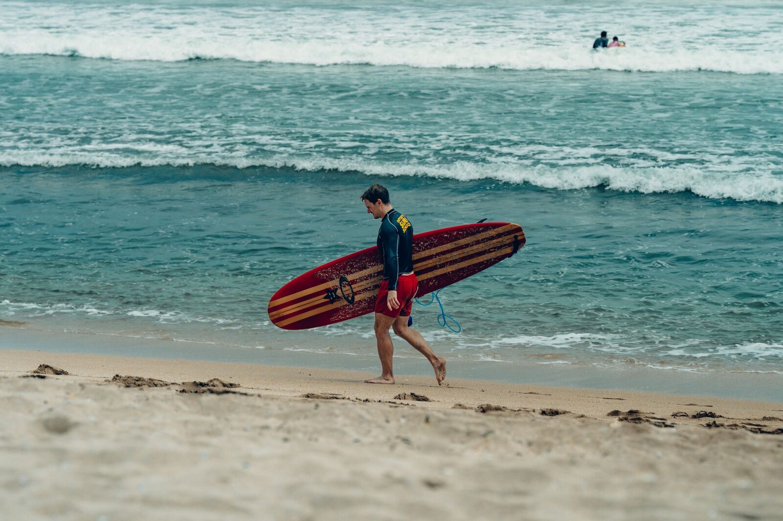 A first-timer heading out with a soft-top board — Kuta is where half of Bali learns to surf.