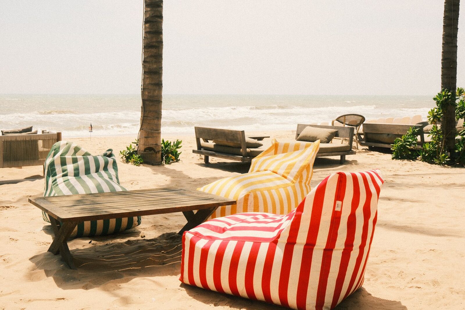 Striped bean-bags on the sand outside a beachfront club.