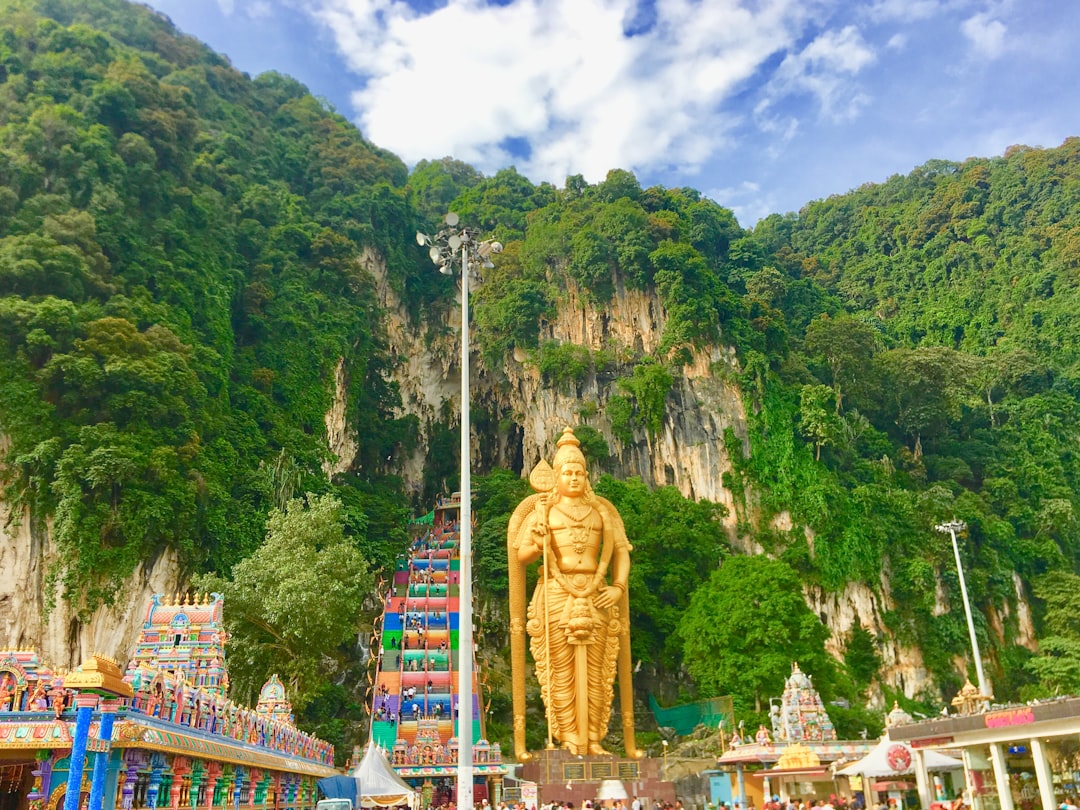 The giant gold Murugan statue below the limestone hill at Batu Caves.