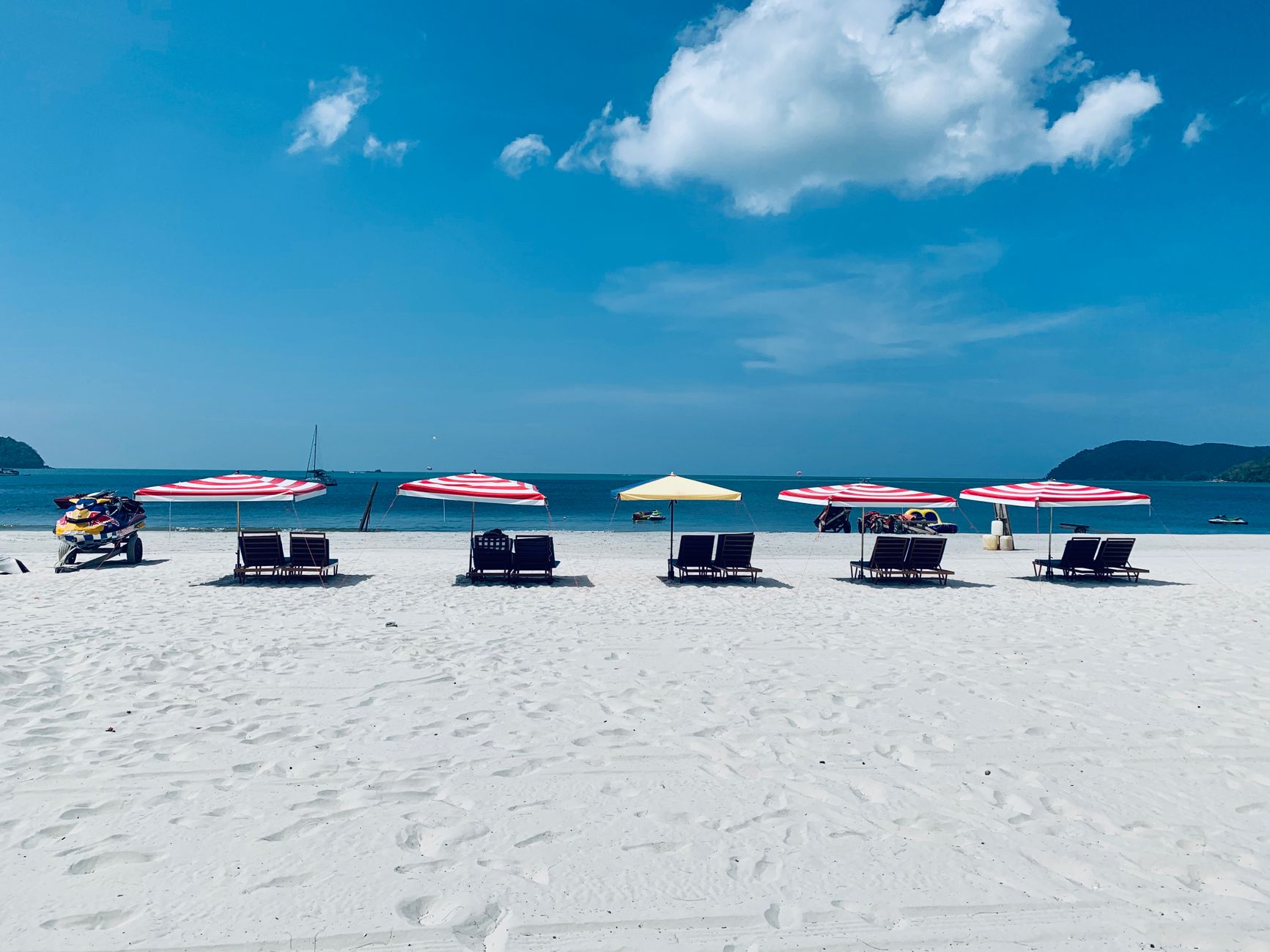 Sun loungers and umbrellas on a bright west-coast Langkawi beach.
